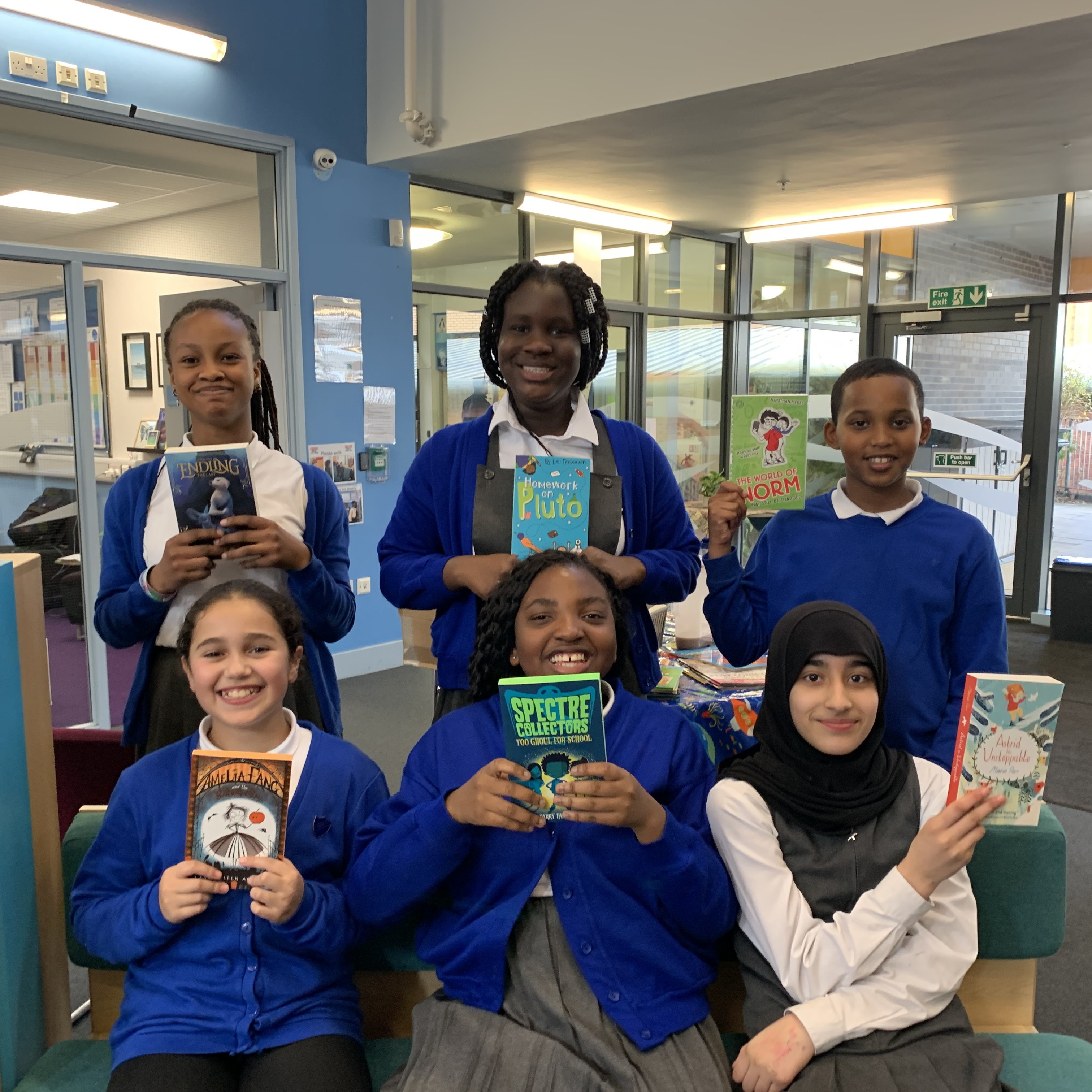 Students at George Dixon Primary School smiling and posing with their favourite books, which were donated by the Smile Education recruitment team